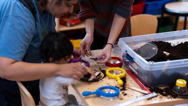 A child looking at worms through a magnifying glass